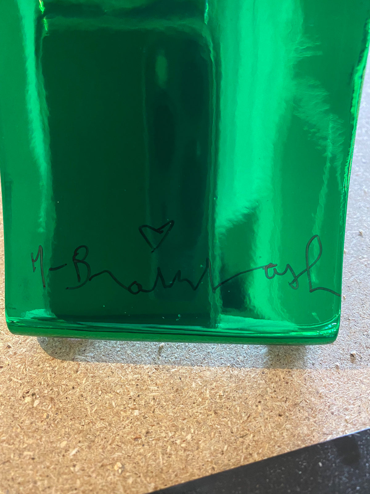 A green reflective piece of metal with a signature on it