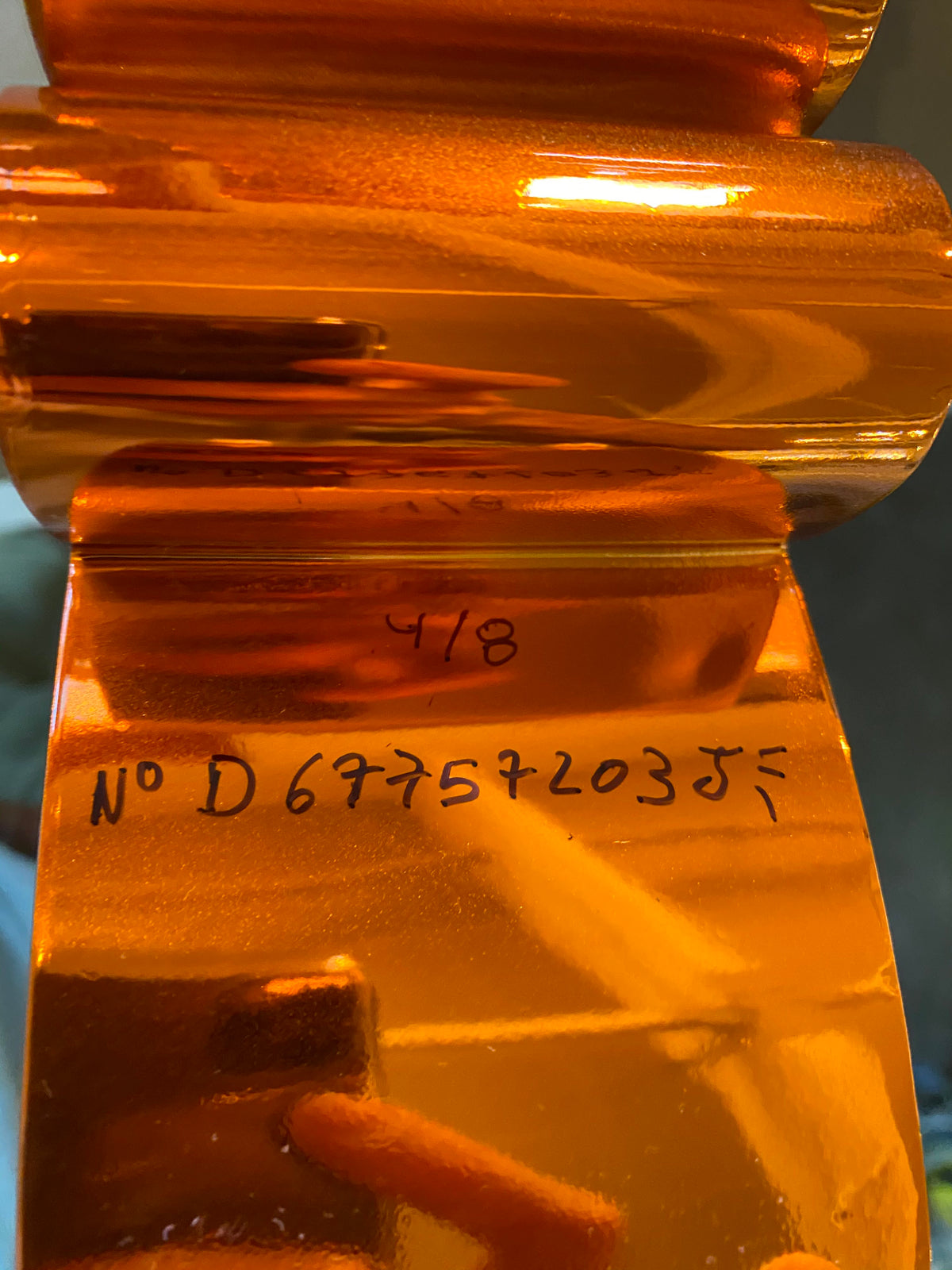 anImage of a reflective piece of orange metal with numbers on it